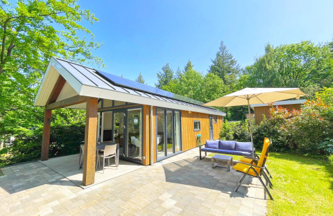 Eco Cottage moderno a De Thijmse Berg, Paesi Bassi, con pannelli solari e area relax all’aperto immersa nel verde.