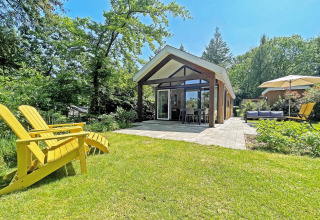 Eco Cottage moderno en De Thijmse Berg, Países Bajos, rodeado de jardín verde y muebles de exterior.