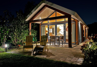 Eco Cottage en De Thijmse Berg, Países Bajos, de noche, con patio iluminado y modernos muebles exteriores.