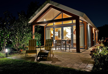 Oplyst Eco Cottage ved De Thijmse Berg i Holland om natten, med terrassemøbler og moderne arkitektur.