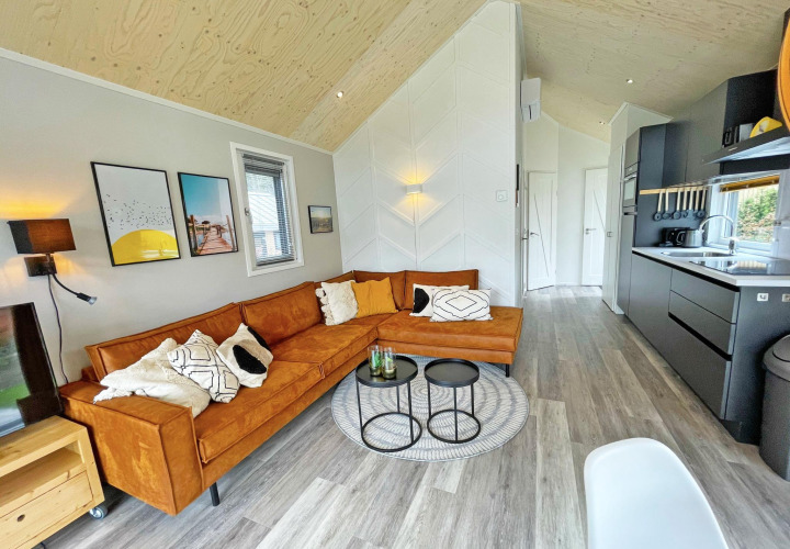 Modernes Wohnzimmer in der Eco Cottage auf De Thijmse Berg, Niederlande, mit orangem Sofa und Küche.
