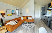 Moderne stue i Eco Cottage på De Thijmse Berg, Nederlandene, med orange sofa og åbent køkken.