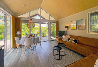 Moderne stue og spisestue i Eco Cottage ved De Thijmse Berg, Holland, med store vinduer og smuk naturudsigt.