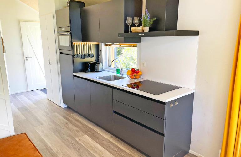 Moderne Küche im Eco Cottage bei De Thijmse Berg, Niederlande, mit grauen Schränken und weißen Arbeitsplatten.