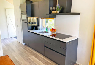 Cucina moderna nell’Eco Cottage a De Thijmse Berg, Paesi Bassi, con mobili grigi e piano bianco.