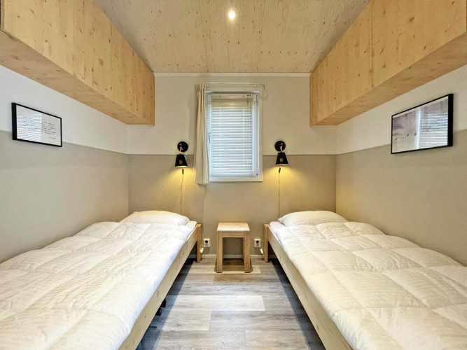 Helles Schlafzimmer im Eco Cottage auf De Thijmse Berg, Niederlande, mit zwei Einzelbetten und Holzdetails.