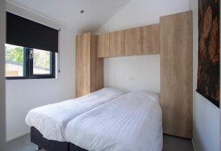 Dormitorio moderno en una Eco Cottage en De Thijmse Berg, Países Bajos, con armarios de madera y luz natural.