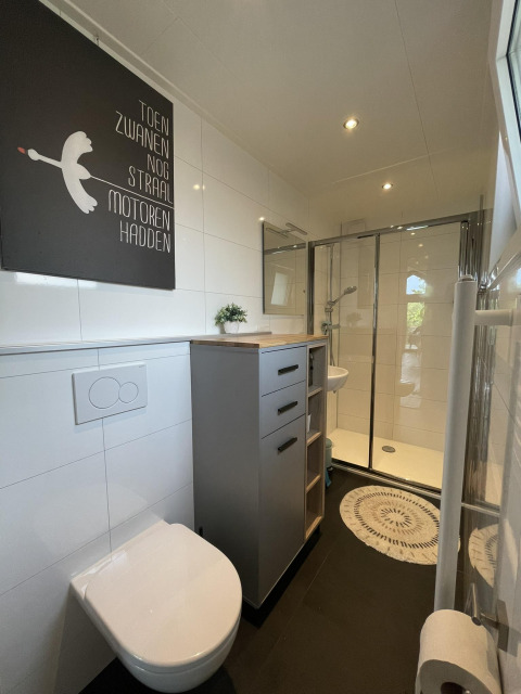 Baño moderno en Eco Cottage, De Thijmse Berg, Países Bajos, con ducha, inodoro y decoración en la pared.