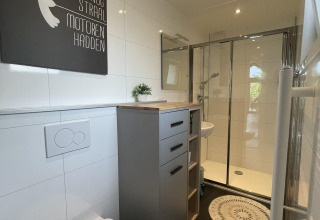 Baño moderno en Eco Cottage, De Thijmse Berg, Países Bajos, con ducha, inodoro y decoración en la pared.