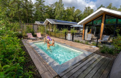 Udendørs pool ved Pool Lodge på De Thijmse Berg i Holland, omgivet af skov og moderne ferieboliger.