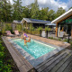 Piscine extérieure à Pool Lodge, De Thijmse Berg, Pays-Bas, entourée de forêt et de maisons de vacances modernes.