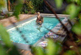 Twee personen genieten van een privébuitenbad met houten terras bij De Thijmse Berg in Nederland.