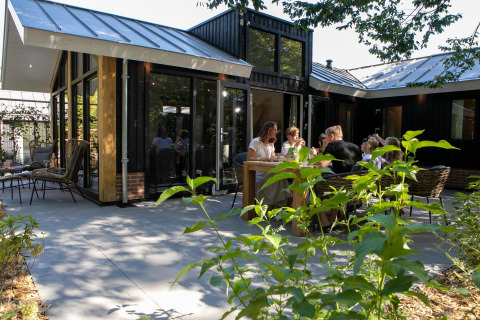 Buitenterras aan Pool Lodge op De Thijmse Berg in Nederland, mensen genieten samen van het zonnige weer.