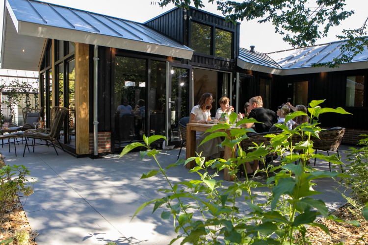 Terraza exterior en Pool Lodge, De Thijmse Berg, Países Bajos, personas disfrutando de un almuerzo soleado juntas.