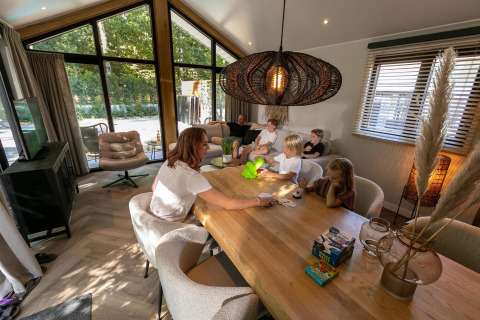 Familia se divierte jugando juntas en Pool Lodge en De Thijmse Berg, Países Bajos, sentados a la mesa.