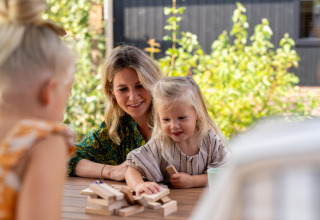 Una madre e i suoi figli giocano insieme a Jenga a un tavolo presso Pool Lodge a De Thijmse Berg, Paesi Bassi.