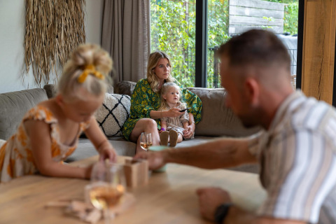 Familia relajándose en la Pool Lodge de De Thijmse Berg, Países Bajos, con niños y decoración acogedora.