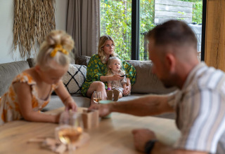 Familia relajándose en la Pool Lodge de De Thijmse Berg, Países Bajos, con niños y decoración acogedora.