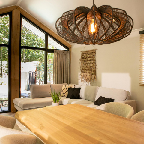 Sala moderna en Pool Lodge de De Thijmse Berg, Países Bajos, con sofá, mesa de madera y lámpara decorativa.