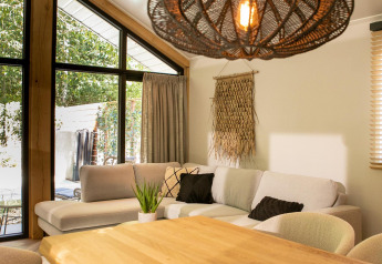 Sala moderna en Pool Lodge de De Thijmse Berg, Países Bajos, con sofá, mesa de madera y lámpara decorativa.