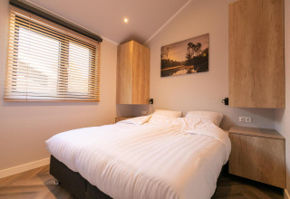 Moderne slaapkamer in Pool Lodge op De Thijmse Berg, Nederland, met houten kasten en groot raam.