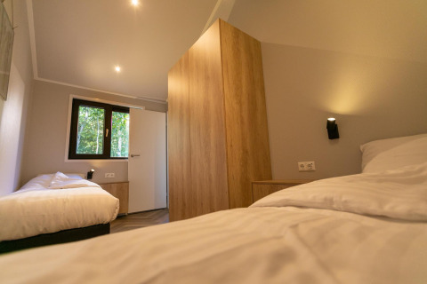 Dormitorio moderno en Pool Lodge de De Thijmse Berg, Países Bajos, con dos camas individuales y madera.