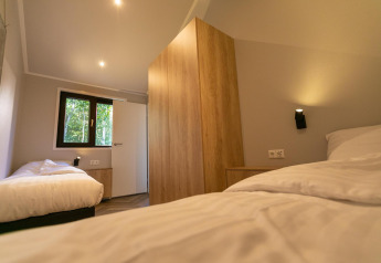 Moderne soveværelse i Pool Lodge ved De Thijmse Berg, Nederlandene, med to enkeltsenge og træinventar.