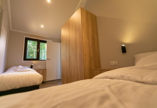 Dormitorio moderno en Pool Lodge de De Thijmse Berg, Países Bajos, con dos camas individuales y madera.