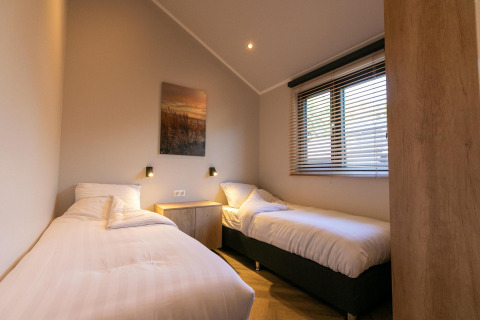 Dos camas individuales en una habitación luminosa de Pool Lodge en De Thijmse Berg, Países Bajos, decoración moderna.