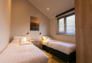 Due letti singoli in una camera luminosa di Pool Lodge a De Thijmse Berg, Paesi Bassi, con arredamento moderno.