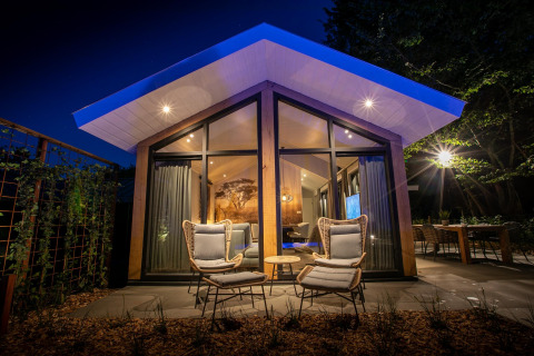 Vista nocturna de Pool Lodge en De Thijmse Berg, Países Bajos, con arquitectura moderna y luz cálida.