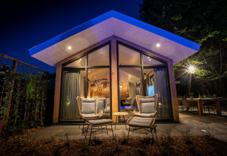 Vista nocturna de Pool Lodge en De Thijmse Berg, Países Bajos, con arquitectura moderna y luz cálida.