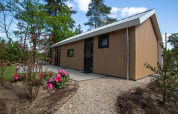 Eco Cottage Comfort lodge op De Thijmse Berg, Nederland, omgeven door bloemen en bomen.