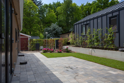 Tuin met gras, bestrating en moderne lodges bij Eco Cottage Comfort, De Thijmse Berg, Nederland.