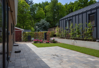 Patio con césped, losas y cabañas modernas en Eco Cottage Comfort, De Thijmse Berg, Países Bajos.