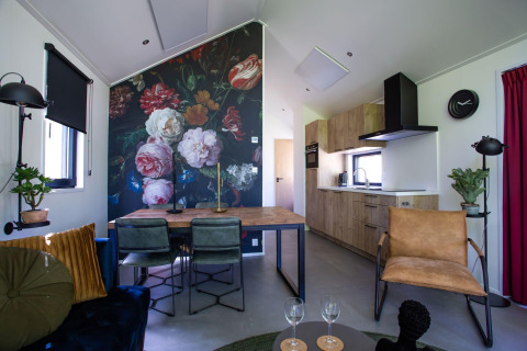 Cottage moderno con murale floreale, tavolo da pranzo, sedute accoglienti e cucina in Eco Cottage Comfort, Olanda.