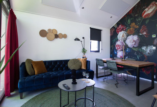 Gezellige living in Eco Cottage Comfort op De Thijmse Berg, Nederland, met opvallende bloemenmuur.