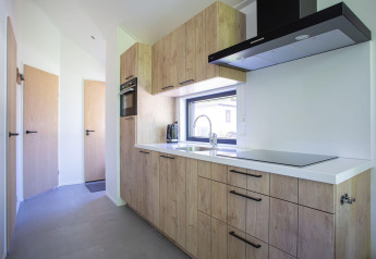 Moderne keuken in Eco Cottage Comfort op De Thijmse Berg, Nederland, met houten kasten en groot raam.