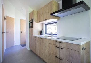 Cocina moderna en Eco Cottage Comfort, De Thijmse Berg, Países Bajos, con armarios de madera y ventana.