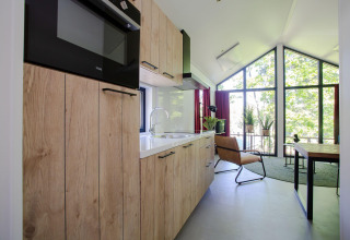Cocina y sala modernas con grandes ventanales y luz natural en Eco Cottage Comfort, De Thijmse Berg.