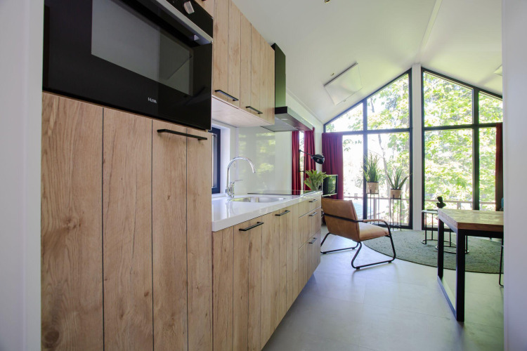 Cocina y sala modernas con grandes ventanales y luz natural en Eco Cottage Comfort, De Thijmse Berg.