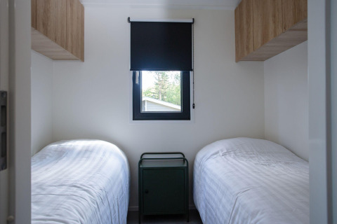 Værelse med to enkeltsenge, et lille natbord og vindue med mørklægningsgardin på Eco Cottage Comfort, De Thijmse Berg.