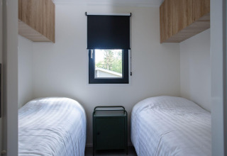 Habitación con dos camas individuales, mesita de noche y ventana en Eco Cottage Comfort, De Thijmse Berg, Países Bajos.