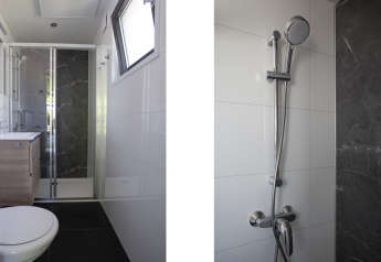 Baño moderno con ducha de vidrio, inodoro y ventana en Eco Cottage Comfort, De Thijmse Berg, Países Bajos.