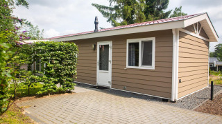 Vista exterior de la Heuvelrug Cottage Comfort en De Thijmse Berg, Países Bajos, rodeada de plantas verdes.