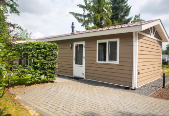 Buitenaanzicht van Heuvelrug Cottage Comfort lodge op De Thijmse Berg in Nederland, omgeven door groen.