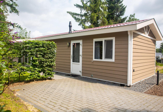 Buitenaanzicht van het Heuvelrug Cottage Comfort verblijf bij De Thijmse Berg in Nederland, omgeven door groen.