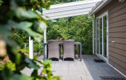 Terraza del Heuvelrug Cottage Comfort en De Thijmse Berg, Países Bajos, con mesa exterior y pérgola blanca.