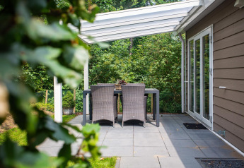 Terras van Heuvelrug Cottage Comfort bij De Thijmse Berg, Nederland, met tuinset en glazen overkapping.