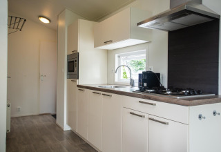 Heldere moderne keuken in Heuvelrug Cottage Comfort op De Thijmse Berg, Nederland, met gaskookplaat.